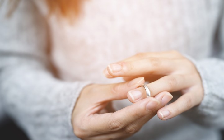 femeie care-și dă jos verigheta după divorț