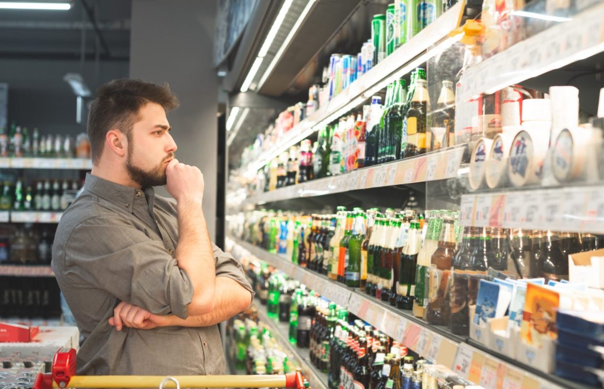 alcoolism - bărbat care cumpără alcool de la supermarket