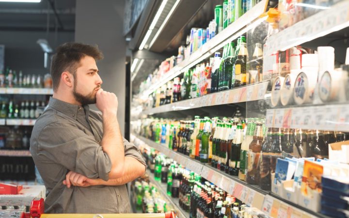 alcoolism - bărbat care cumpără alcool de la supermarket