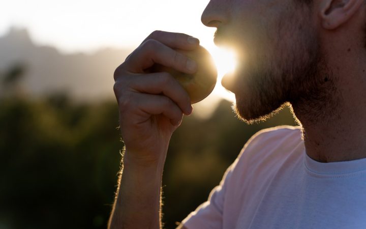 bărbat care mănâncă un măr la răsărit sau la apus