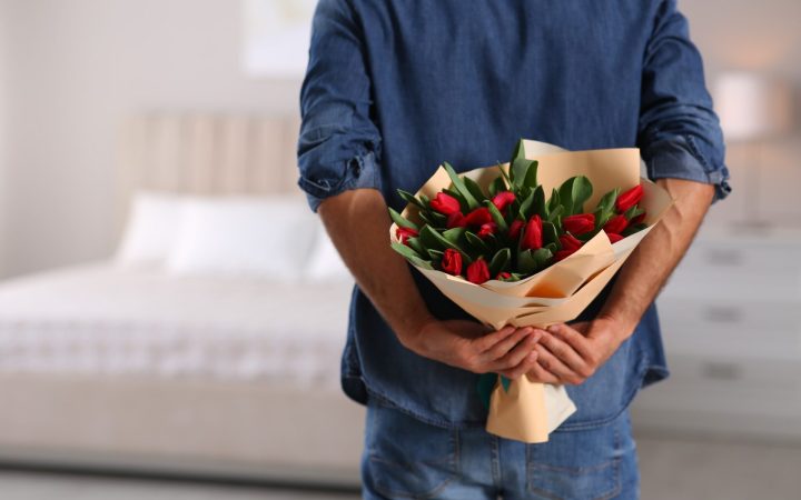 bărbat care ascunde un buchet de lalele la spate pentru parteneră