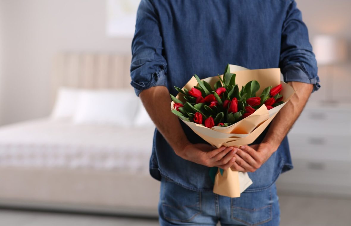 bărbat care ascunde un buchet de lalele la spate pentru parteneră