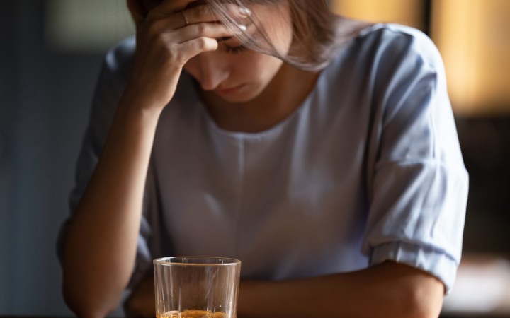 Femeie deprimata cu un pahar cu tărie în față