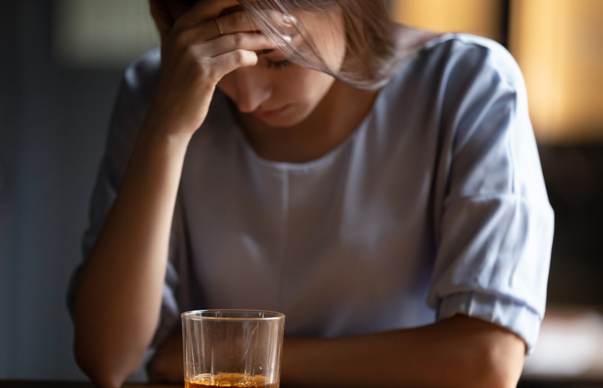 Femeie deprimata cu un pahar cu tărie în față