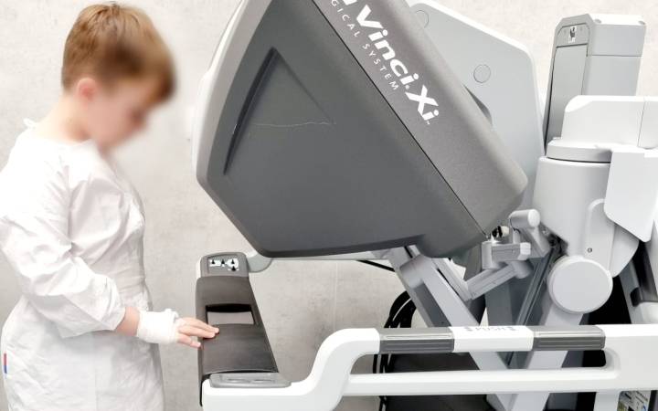 Alexandru, un băiețel în vârstă de 8 ani, se joacă cu robotul da Vinci Xi
