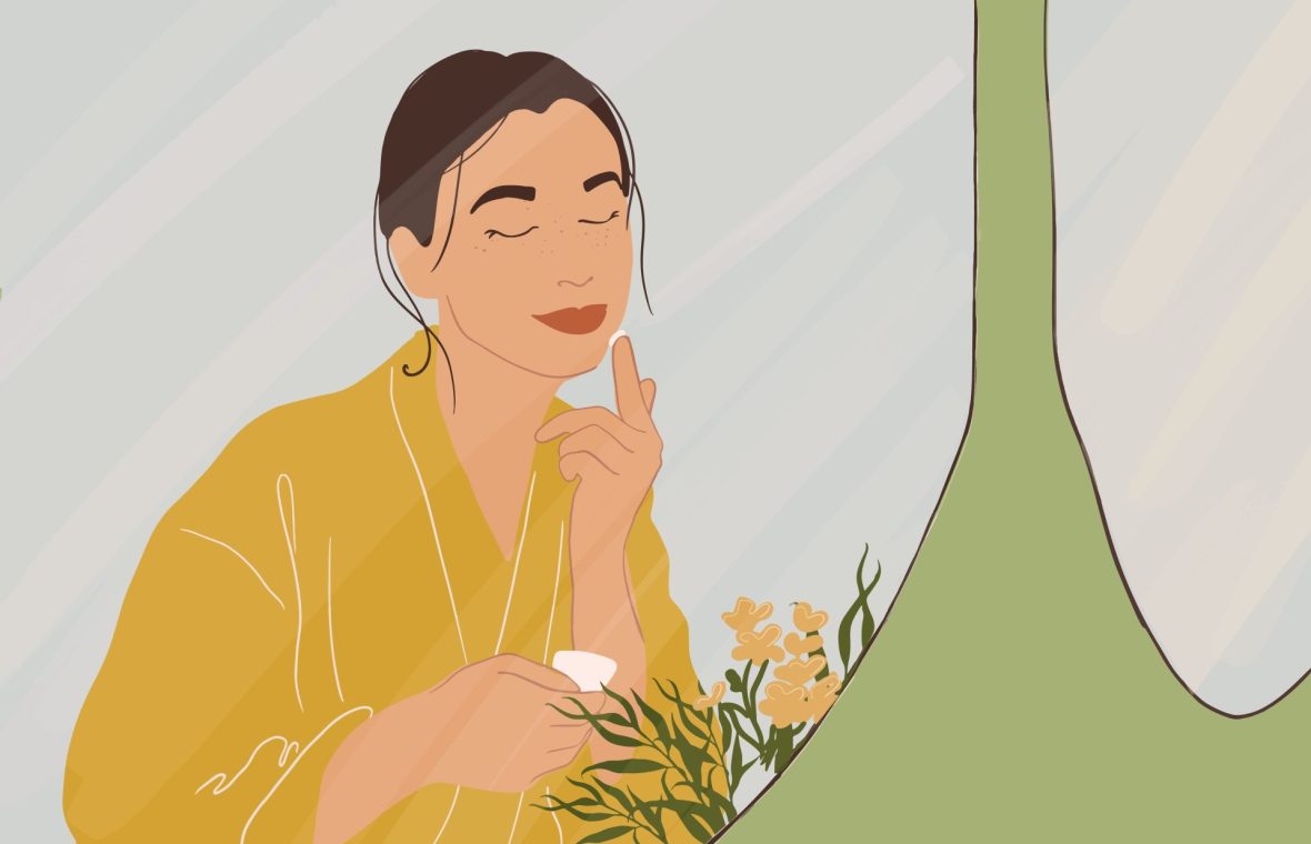 femeie care își aplică pe față o cremă și folosește produse de îngrijire naturale