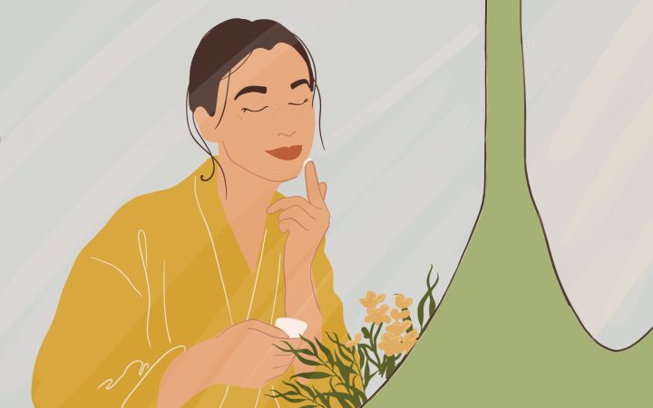 femeie care își aplică pe față o cremă și folosește produse de îngrijire naturale