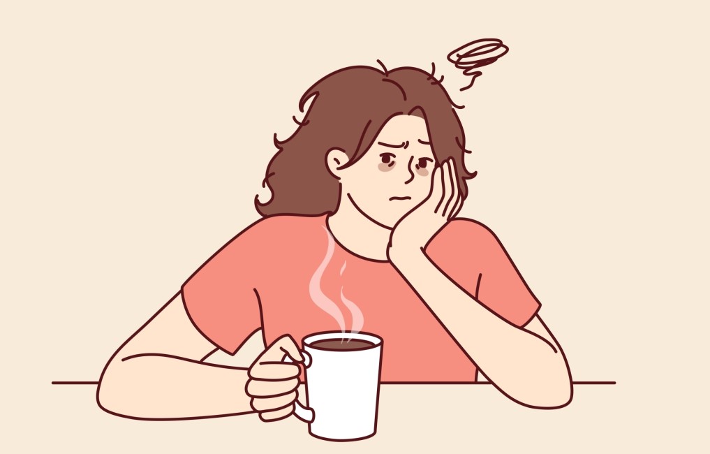 intoleranta la cafea. femeie cu durere de cap in timp ce bea cafea