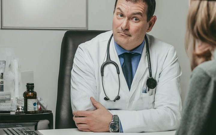 gaslighting-ul medical. medic bărbat care ascultă sceptic, cu sprânceana ridicată, o pacientă
