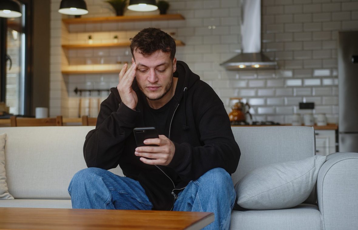 bărbat stresat se uită pe telefon