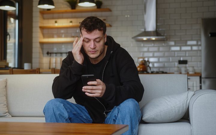 bărbat stresat se uită pe telefon