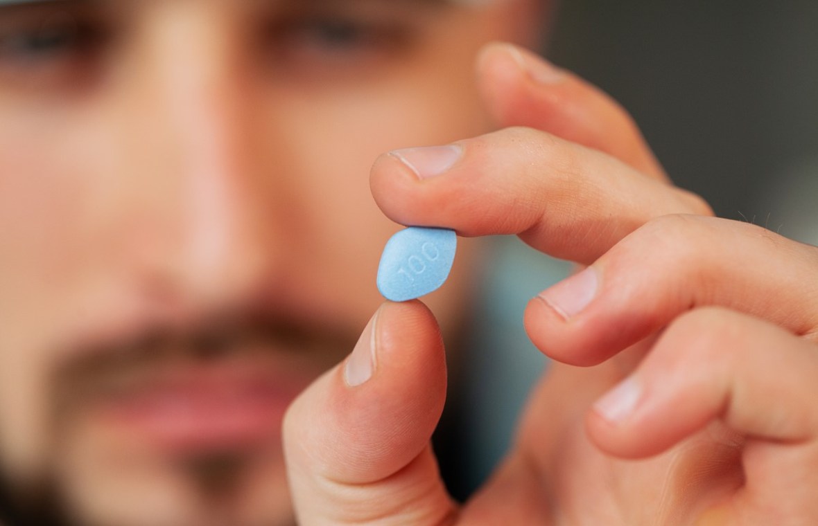 viagra. barbat care are o pastilă albastră în mână