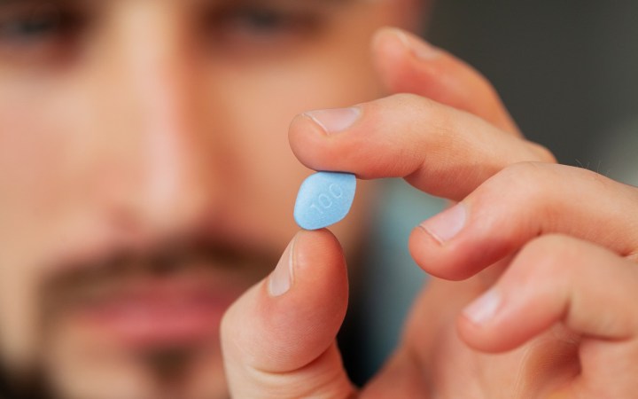 viagra. barbat care are o pastilă albastră în mână