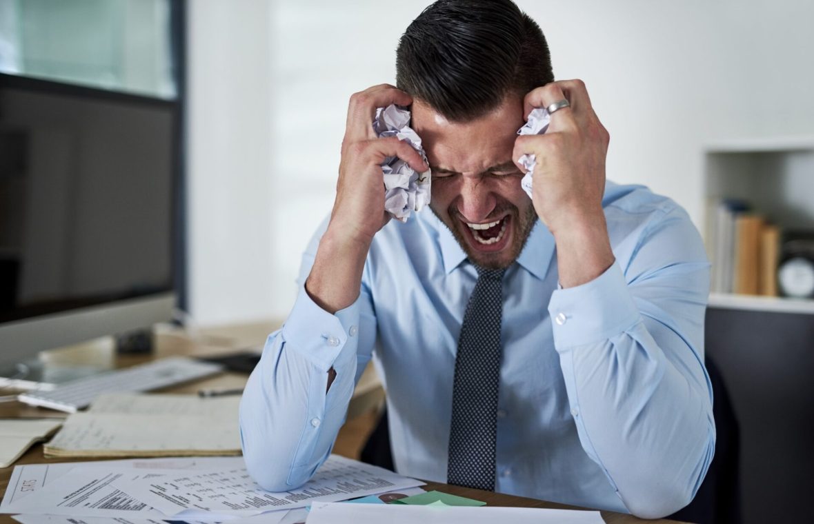 bărbat care face o criză de nervi la birou și rupe hârtiile