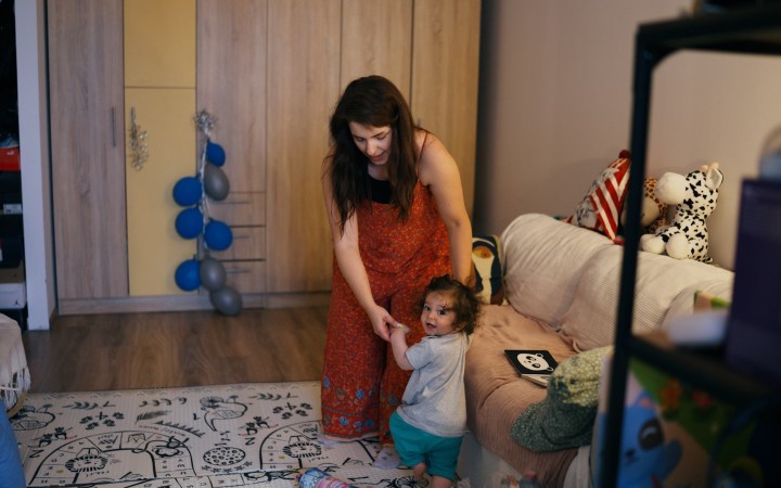 mama, sandra, își susține fiul de 1 an, Anton care învață să meargă în sufragerie