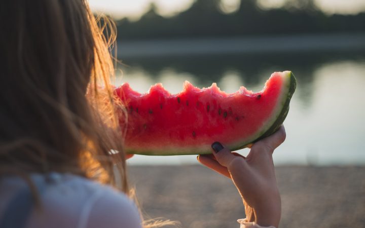 femeie care mănâncă o felie medie de pepene