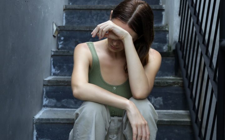 femeie tristă își ascunde fața, pe scări