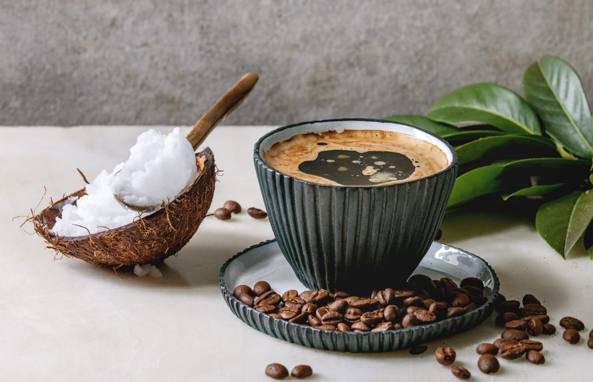 cafea alături de o jumătate de nucă de cocos cu unt/ulei de ccocos