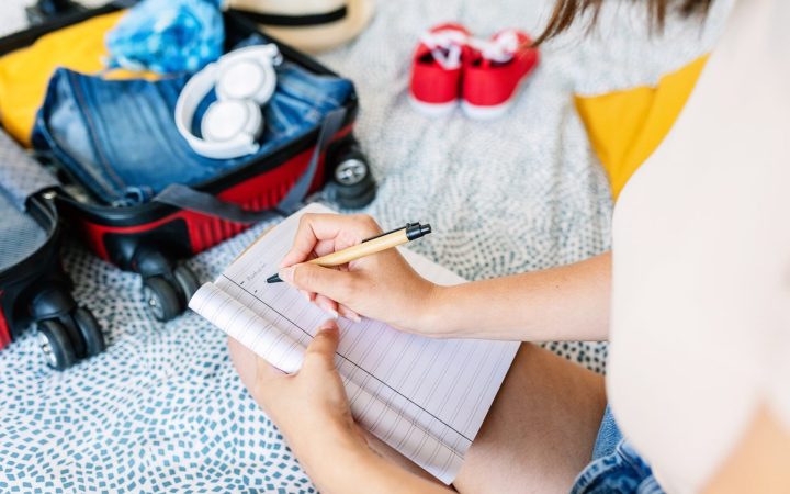 femeie care face lista de bagaje pentru vacanță