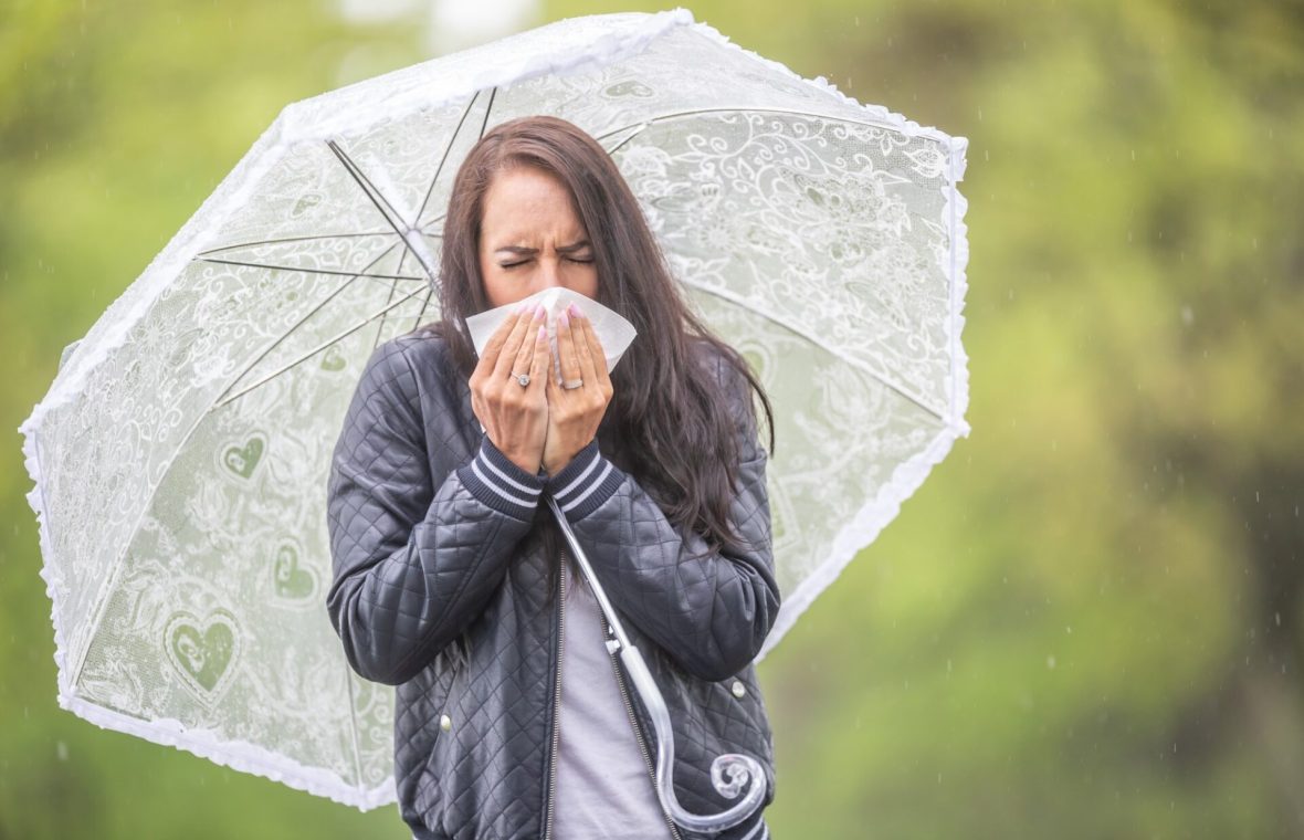 femeie răcită cu umbrelă într- zi ploioasă de toamnă