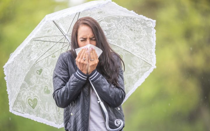femeie răcită cu umbrelă într- zi ploioasă de toamnă