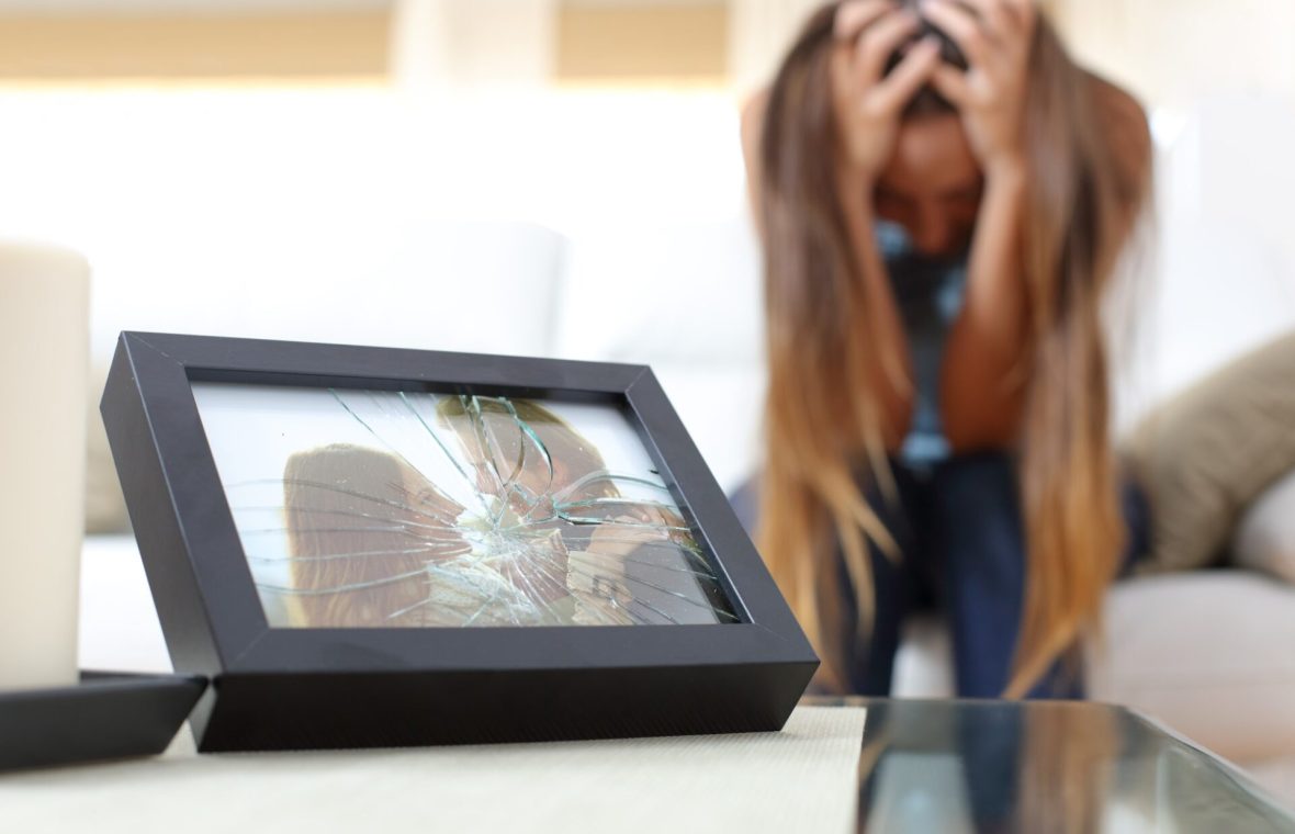 cum să treci peste o despărțire - femeie care plânge lângă o fotografie de cuplu spartă
