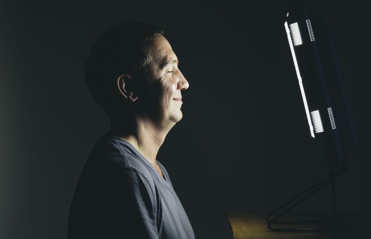 bărbat care face terapie cu lumină, fototerapie și zâmbește