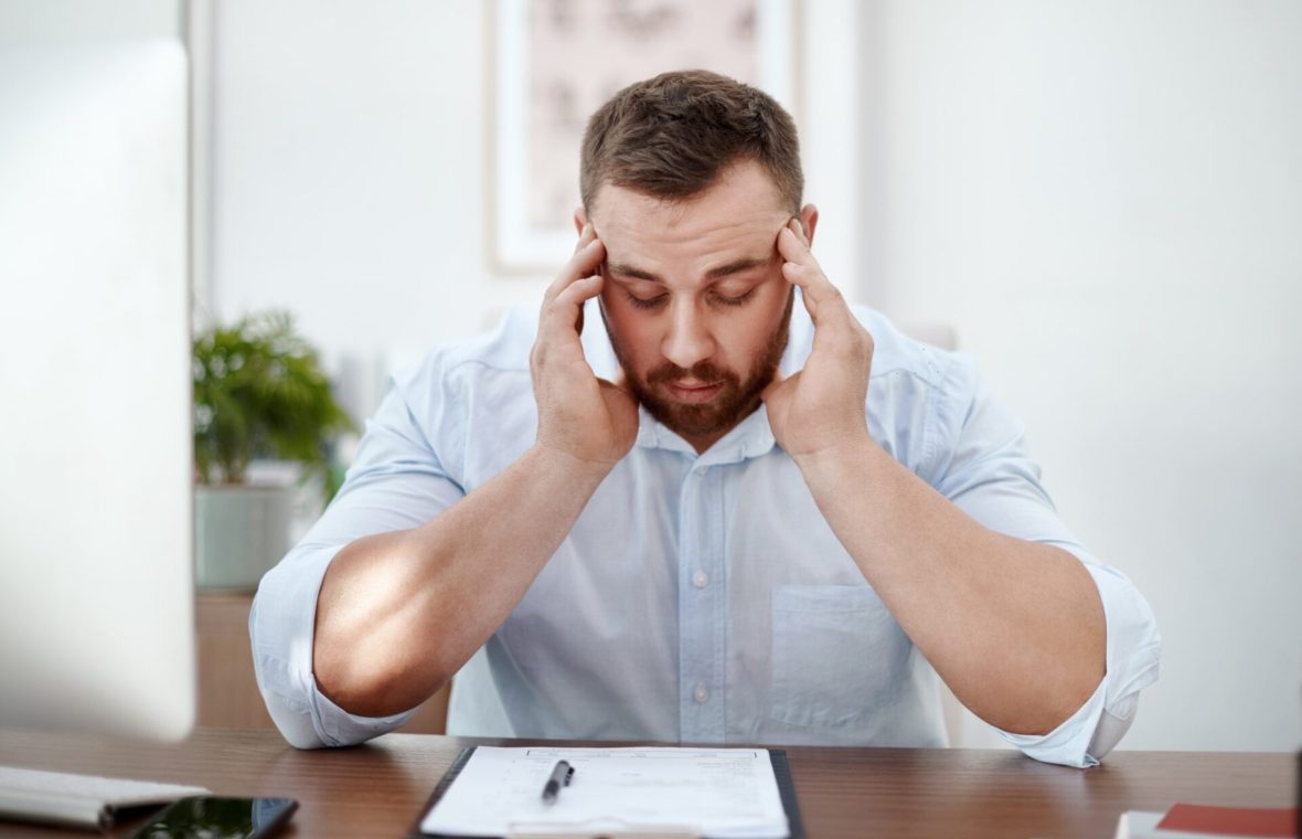 bărbat cu ceață mentală la birou cu durere de cap