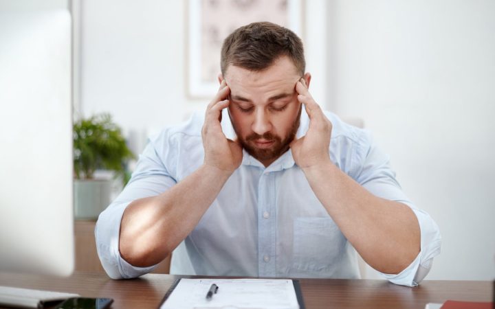 bărbat cu ceață mentală la birou cu durere de cap