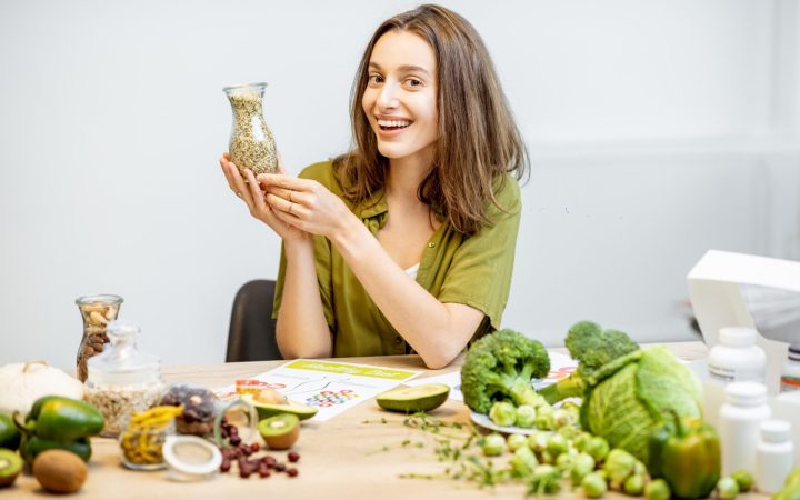 femeie slabă și fericită cu un borcan cu cereale în mână și broccoli și alte alimente din dieta oshawa macrobiotică pe masă