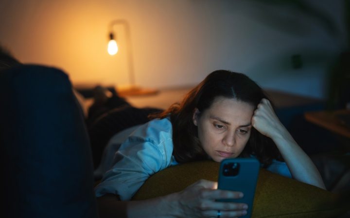femeie îngrijorată face scrolling pe telefon