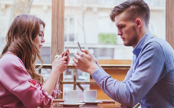 cuplu pe telefon la masă într-o relație de iubire modernă