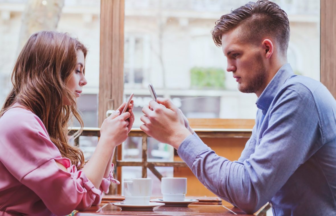 cuplu pe telefon la masă într-o relație de iubire modernă