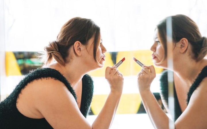 femeie încrezătoare în propria persoană și stimă de sine sănătoasă arată cu rujul spre imaginea din oglindă