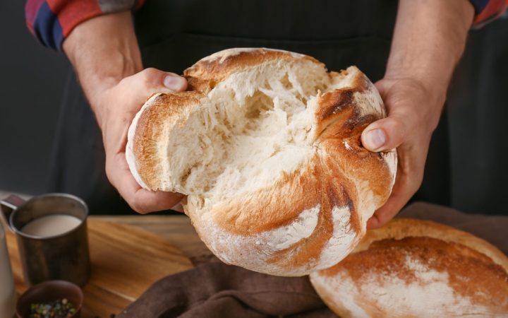 femeie rupe o pâine proaspătă