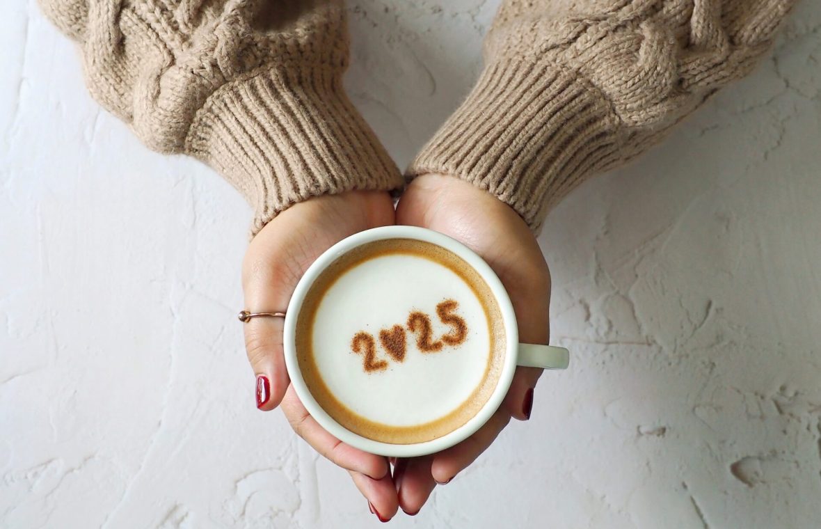 femeie cu pulover mocha mousse și cu o cafea cu spumă de lapte în mână, cu cafea e scris 2025