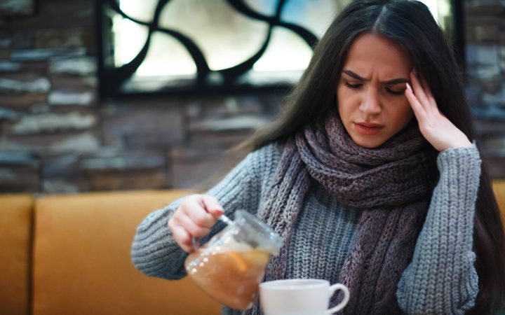 femeie cu durere de cap bea ceai de ghimbir cu lămâie