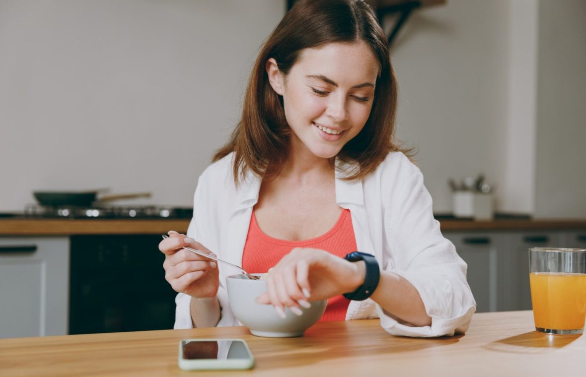 femeie care ia micul dejun și se uită la ceas pentru că ține dieta 16:8