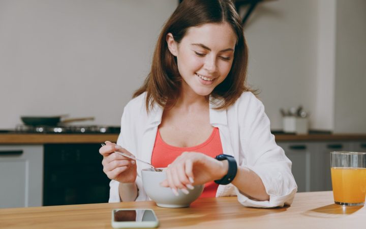 femeie care ia micul dejun și se uită la ceas pentru că ține dieta 16:8
