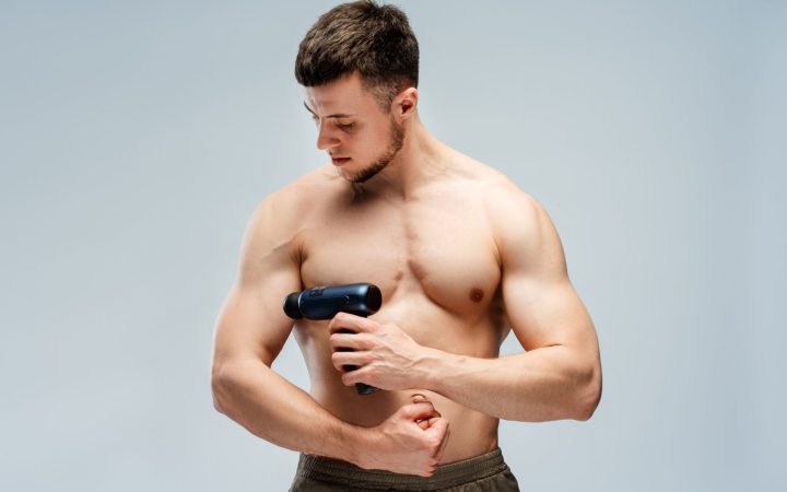 bărbat cu mușchi își face masaj la biceps pentru a combate febra musculară