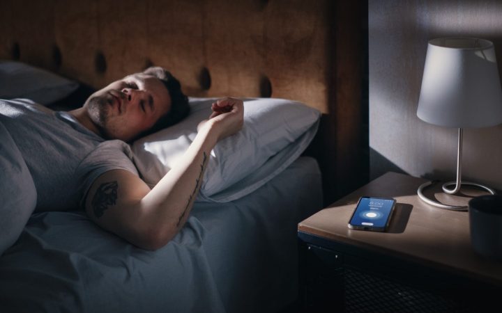 bărbat care doarme și nu e trezit de alarma telefonului - ce se întâmplă când dormi prea mult