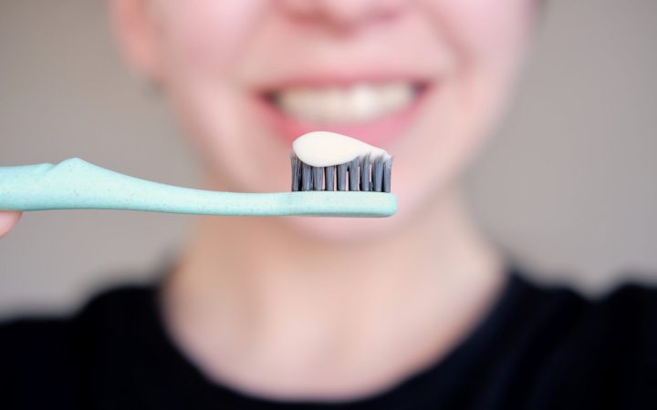 persoană care și-a pus multă pastă de dinți cu fluor pe periuță și face exces