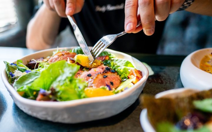 bărbat care mănâncă o salată cu somon și fructe