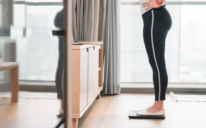 femeie în echipament sportiv care se cântărește
