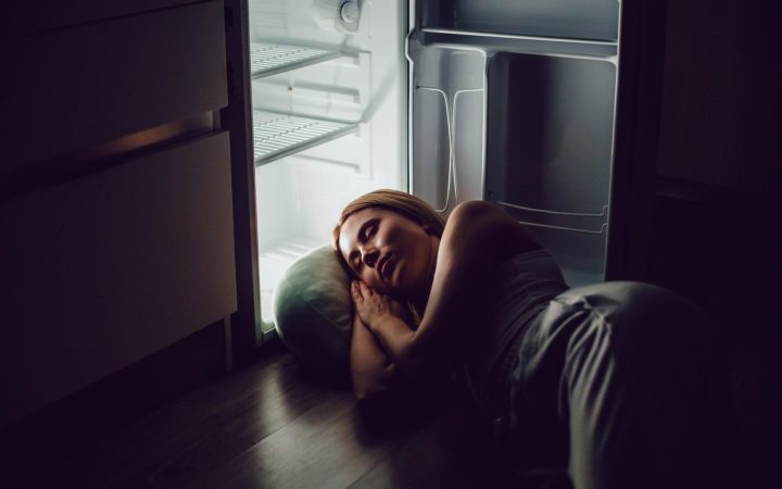 femeie care doarme cu capul în frigider în timpul unui val de căldură