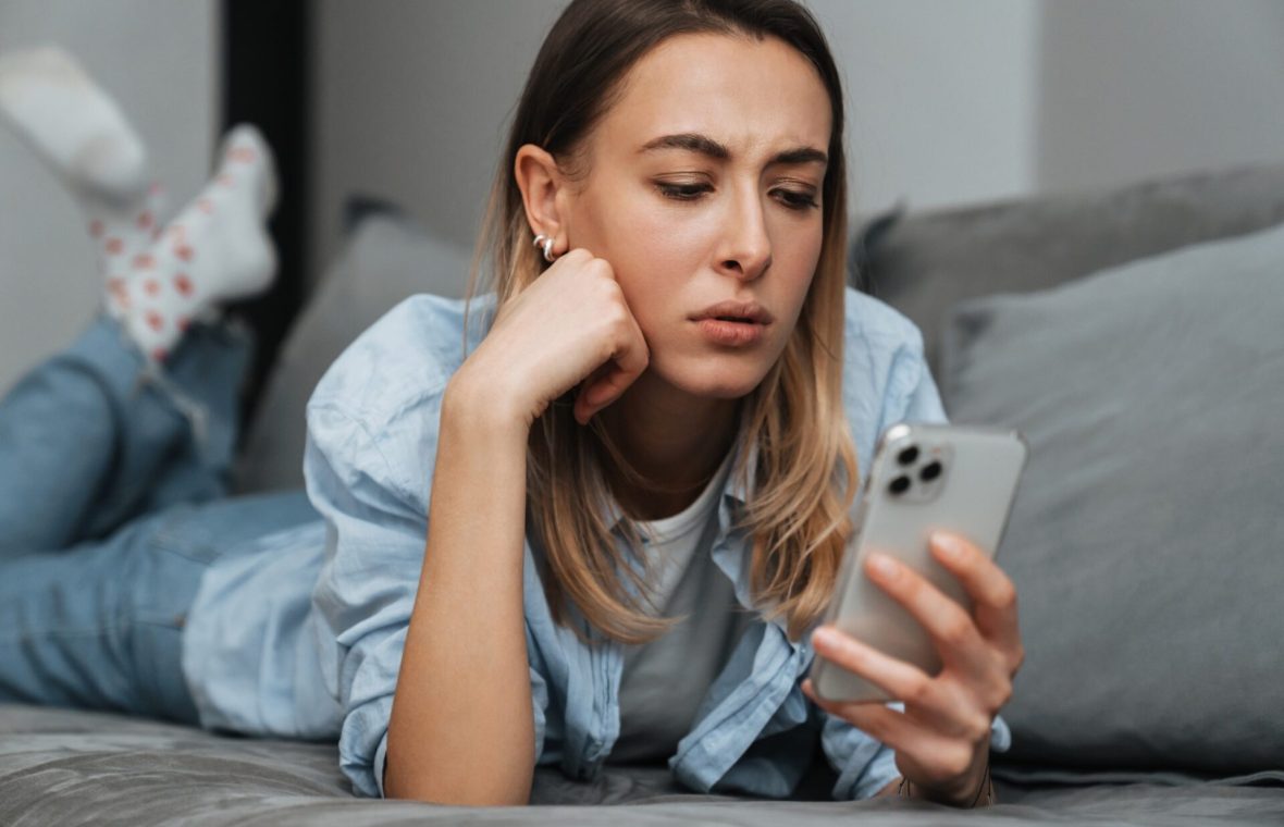 femeie tânără face swipe pe telefon și e indecisă - FOBO