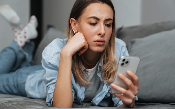 femeie tânără face swipe pe telefon și e indecisă - FOBO