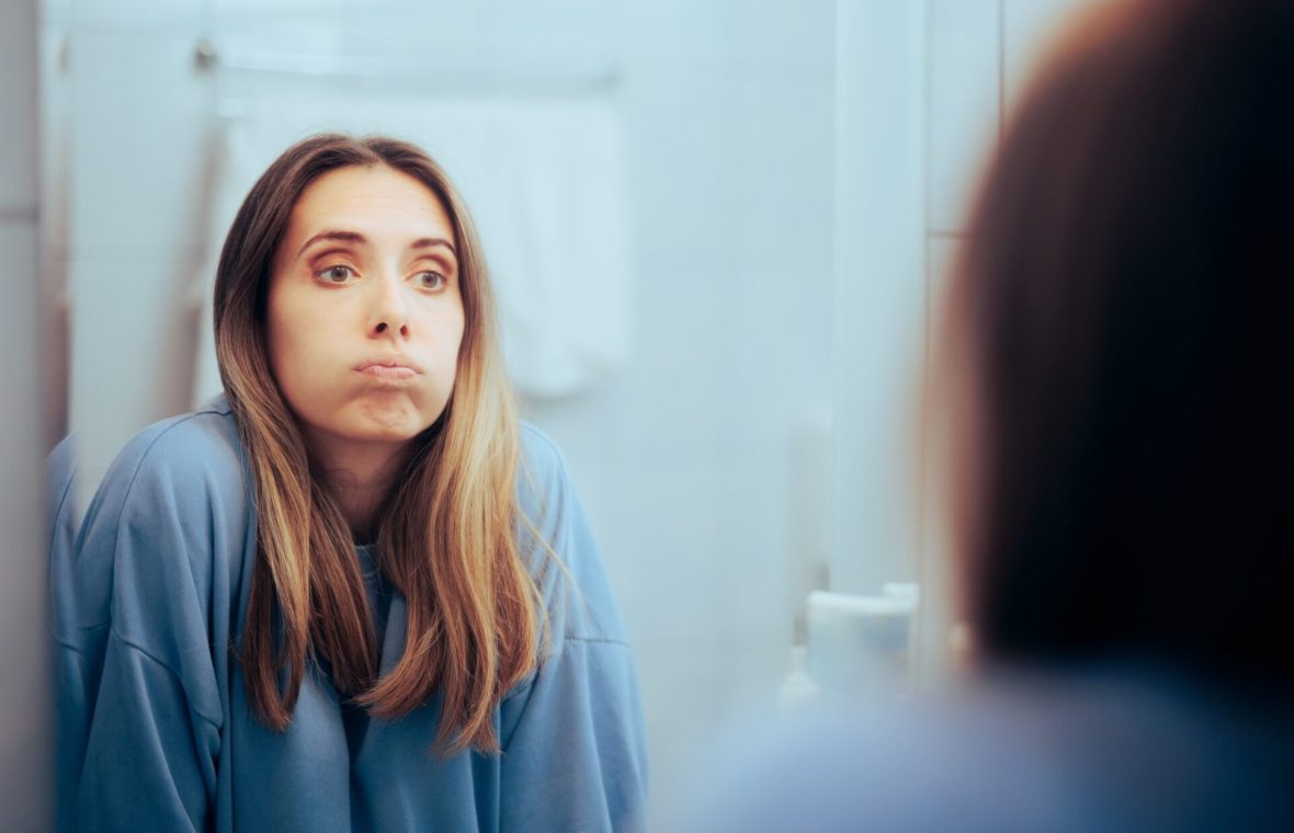 femeie de vârstă mijlocie se uită supărată în oglindă