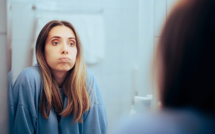 femeie de vârstă mijlocie se uită supărată în oglindă