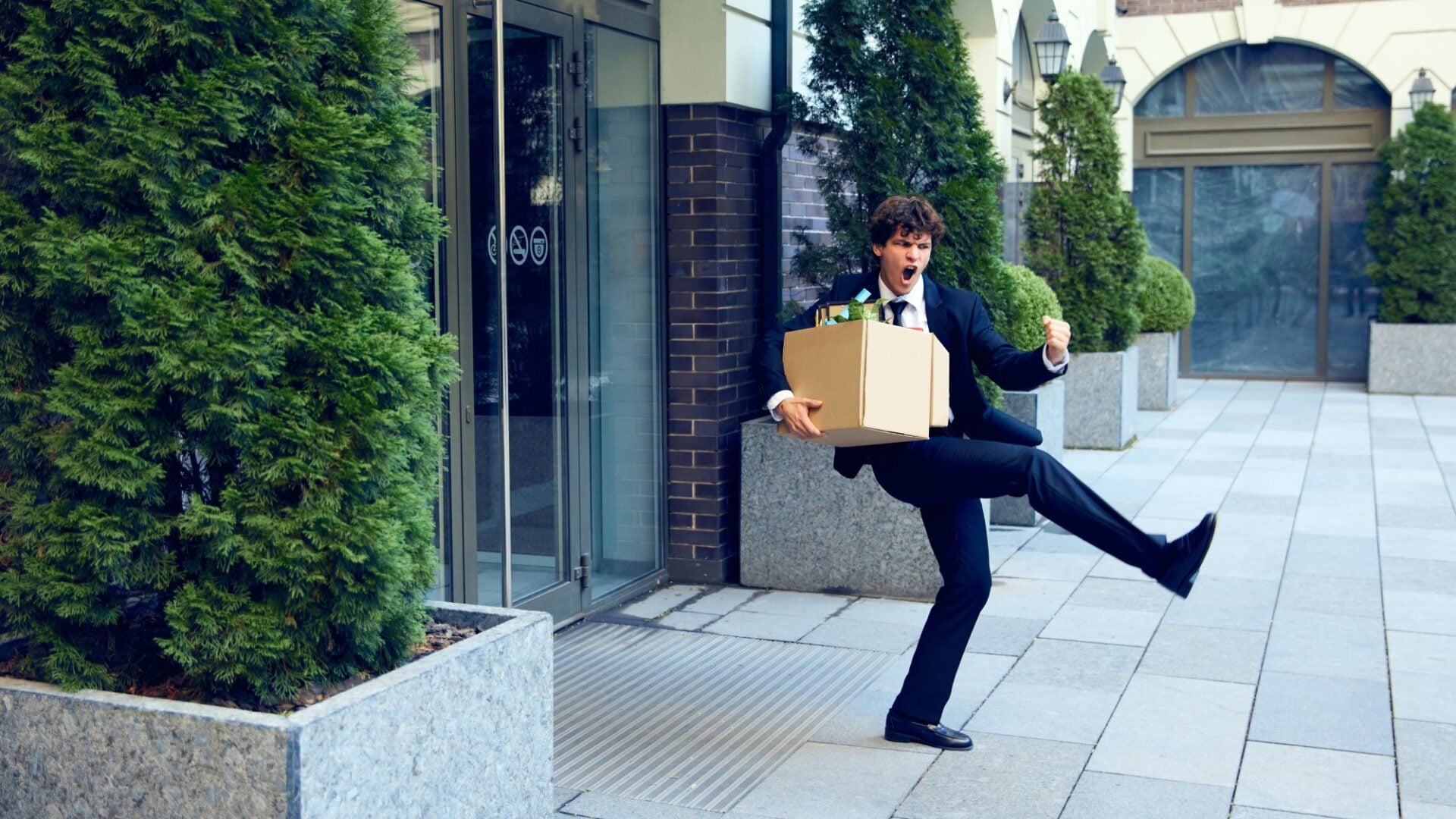 bărbat fericit că și-a dat demisia, dansează cu o cutie cu lucruri personale de la birou